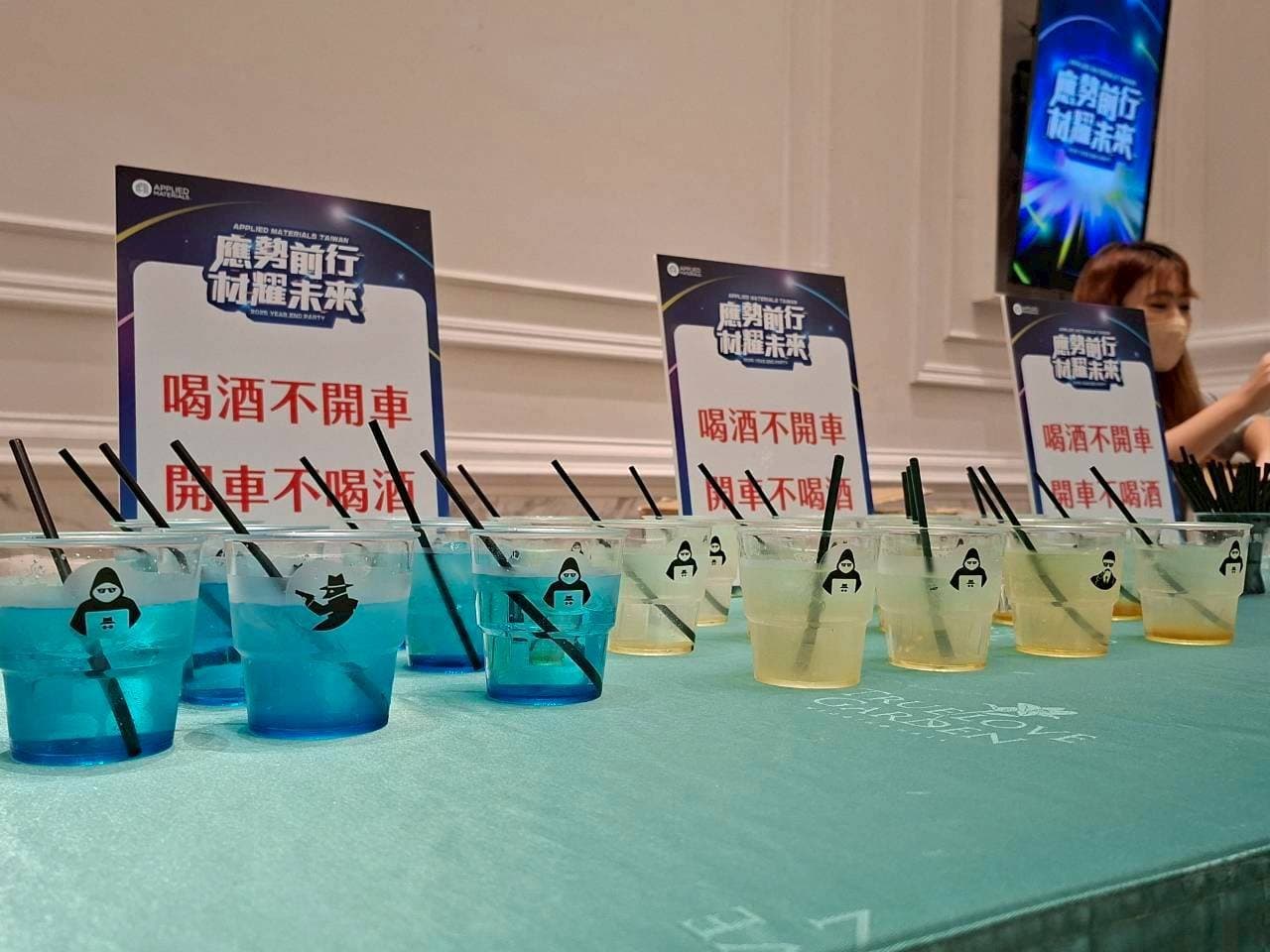 Rows of blue-and-yellow gradient cocktails beside the event signage