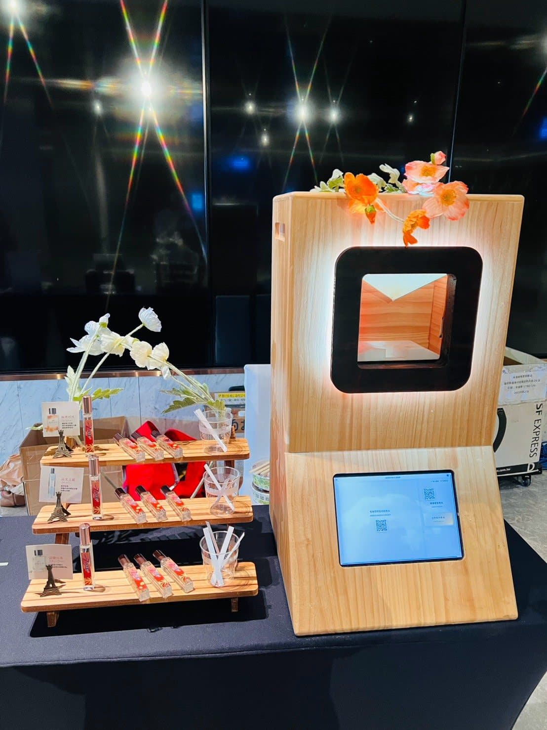 The Scent Machine at an evening gala, its glowing screen set among orange florals