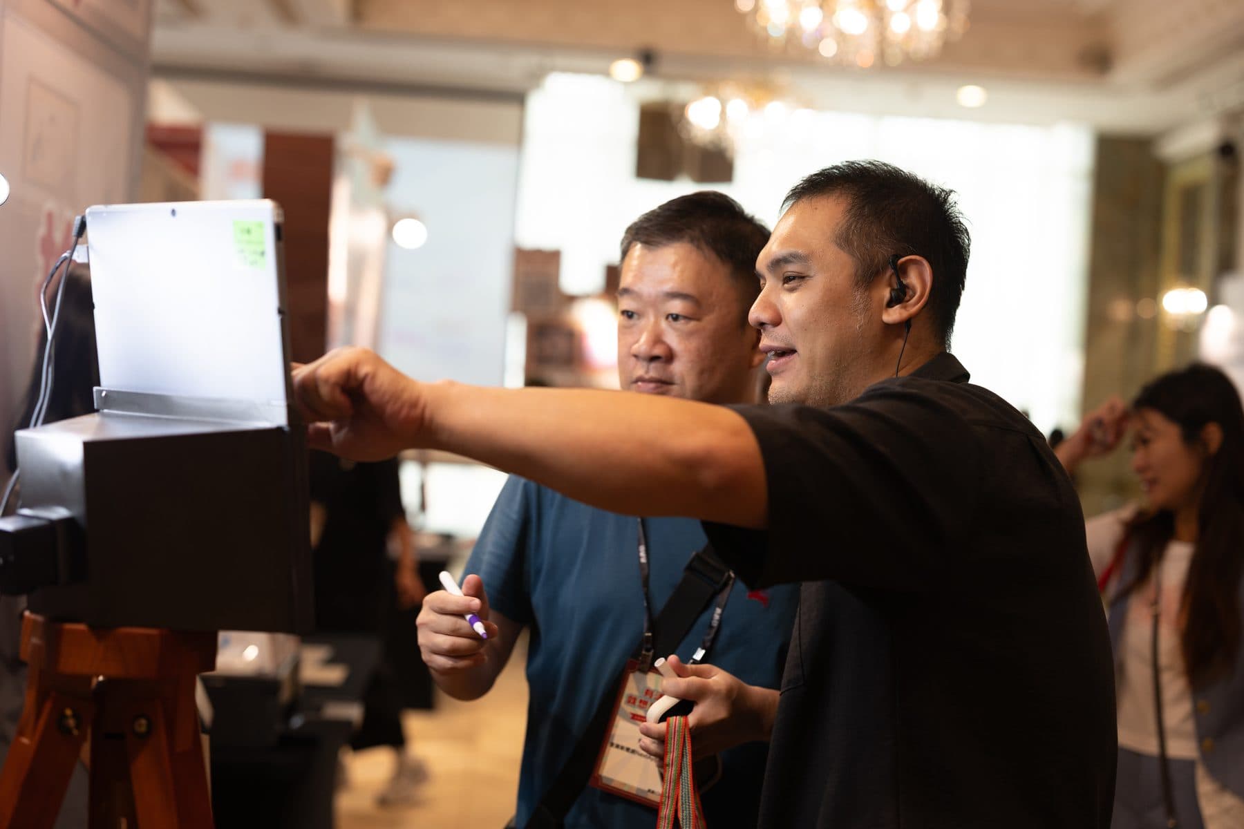 Two guests using the booth with a crew member’s guidance, one holding the stylus