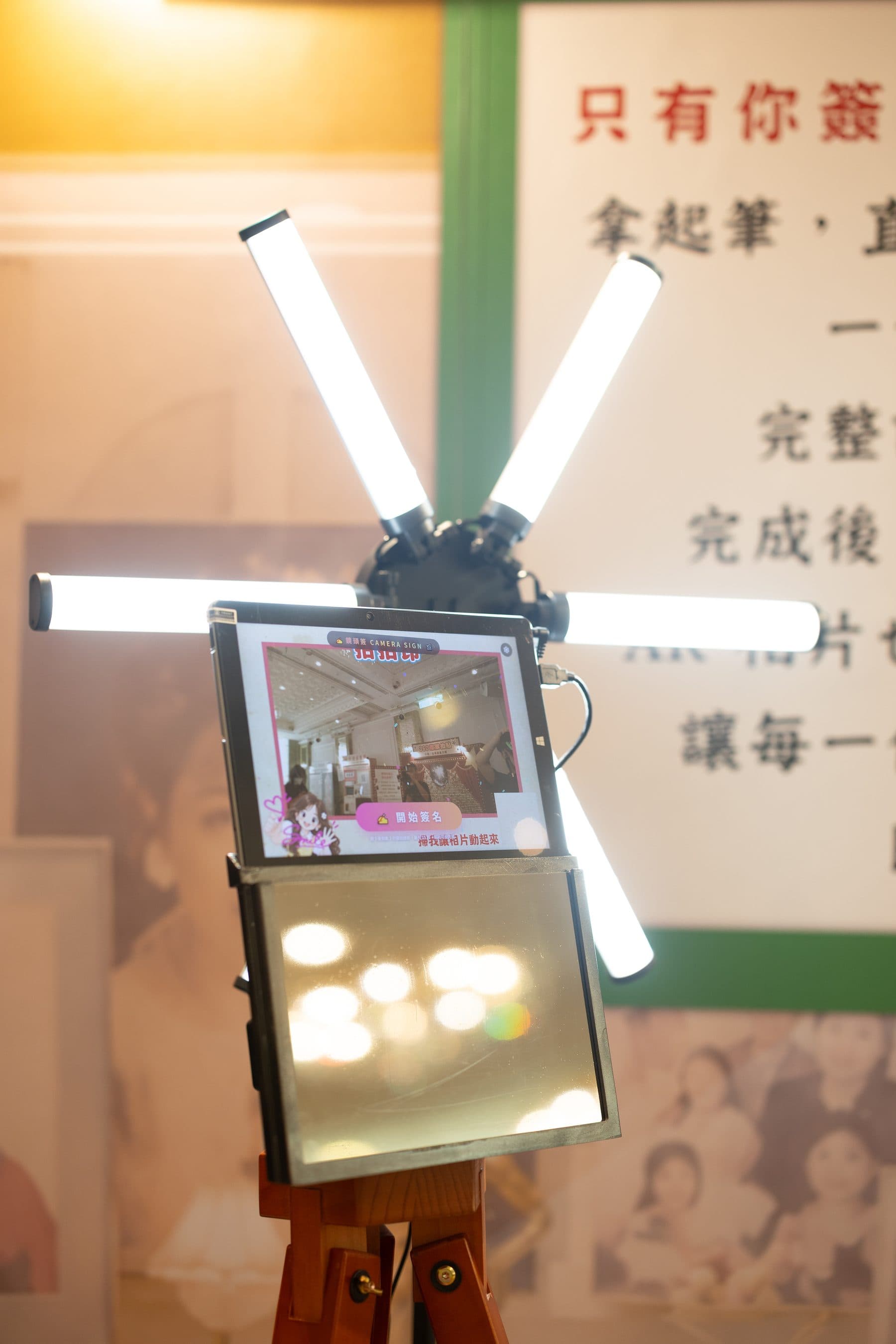 Full view of the camera sign booth on its wooden tripod in front of the experience backdrop