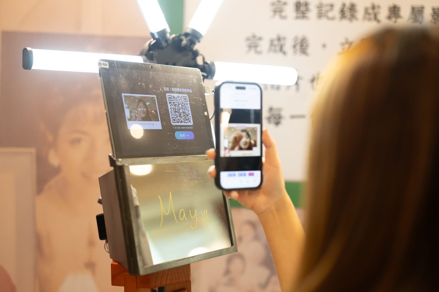 A guest scanning the QR code on the booth screen, their handwritten signature still on the mirrored panel below
