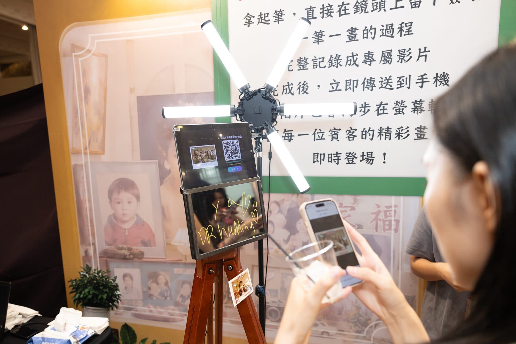 Full view of the booth as a guest scans the on-screen QR code, prints hanging below