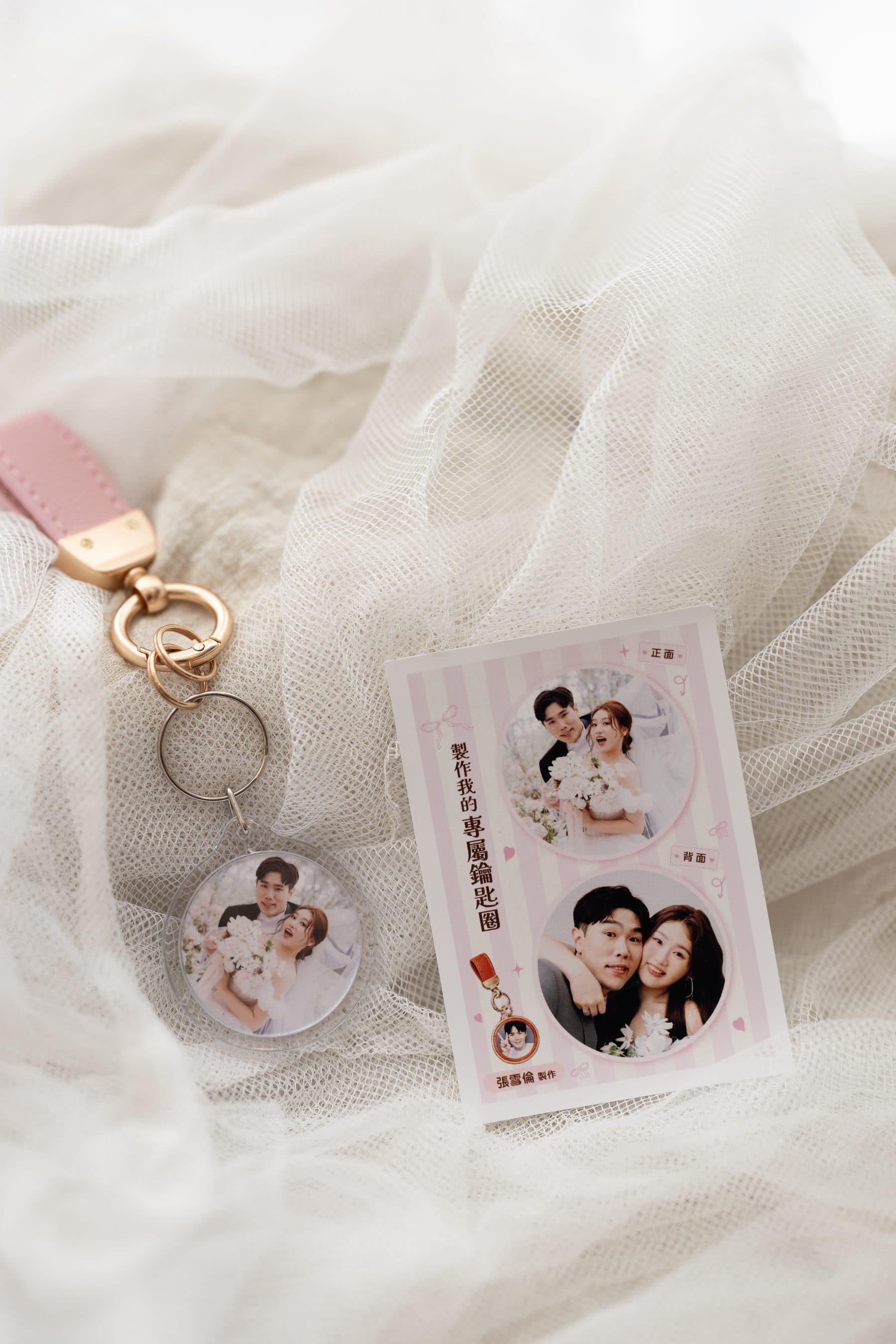 A pink-strapped acrylic keyring beside a matching printed card carrying the same photo
