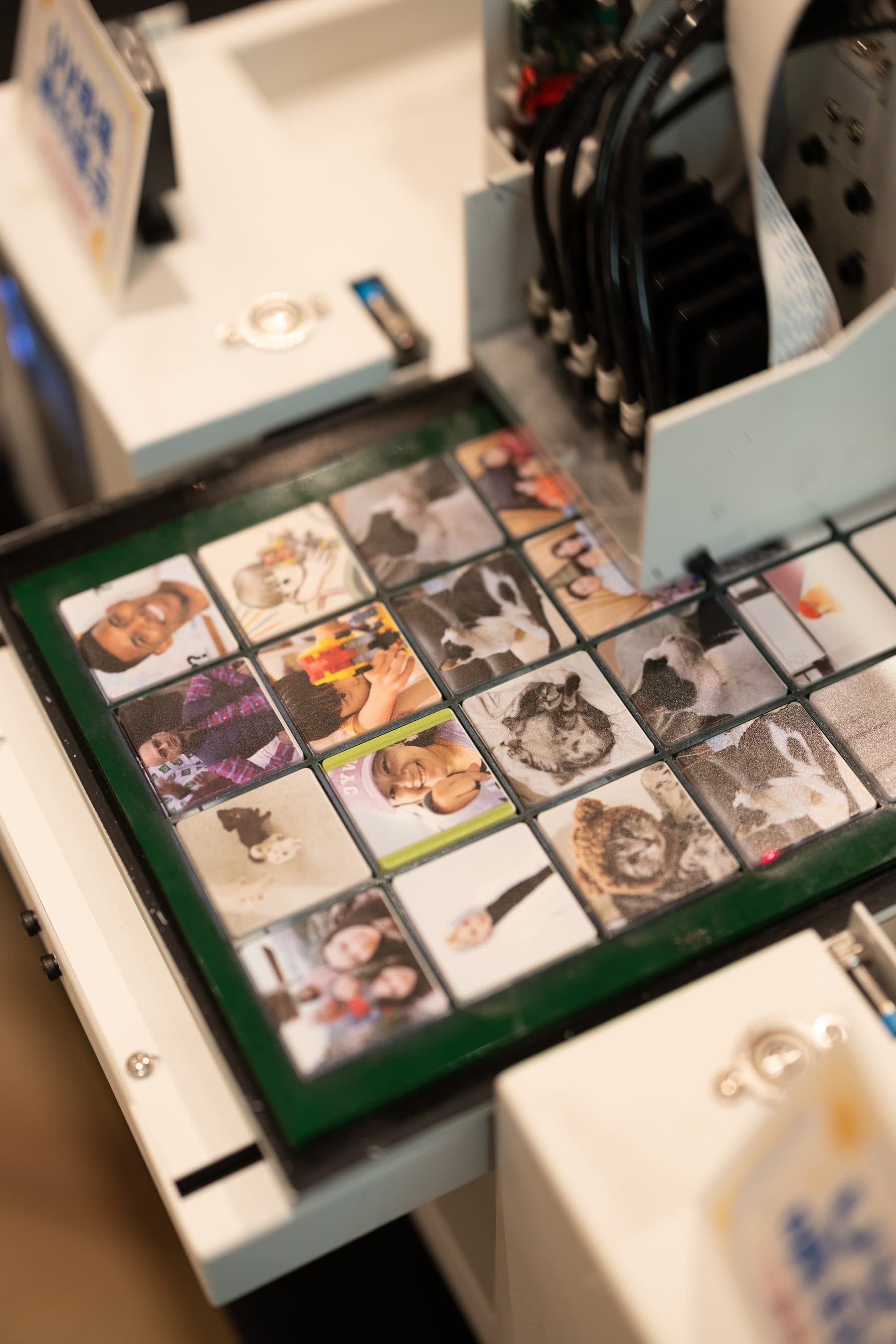 The print head laying down small square panels on a green jig, showing portraits and pet photos