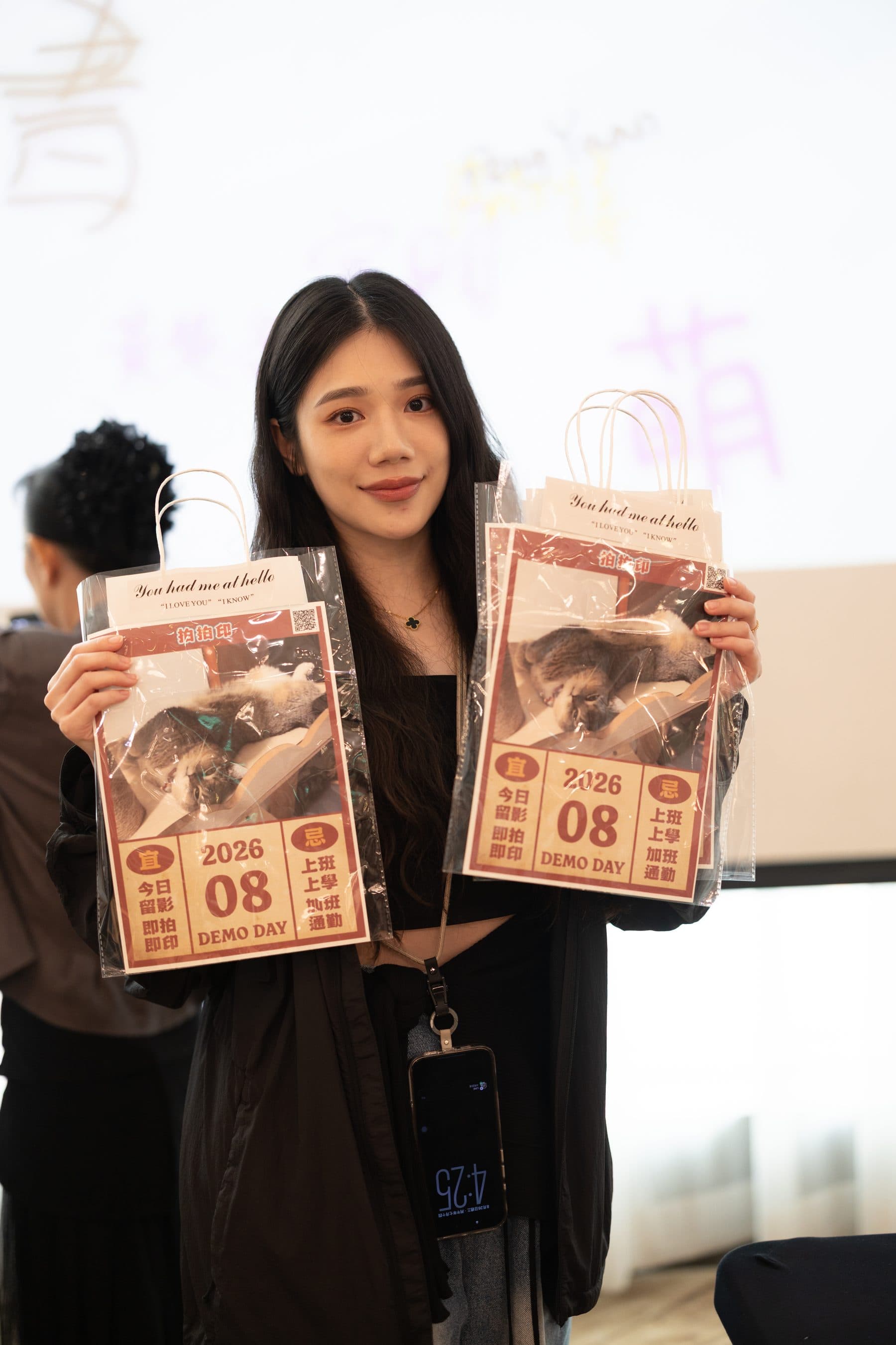 A guest holding two copies with a “2026 08 DEMO DAY” masthead