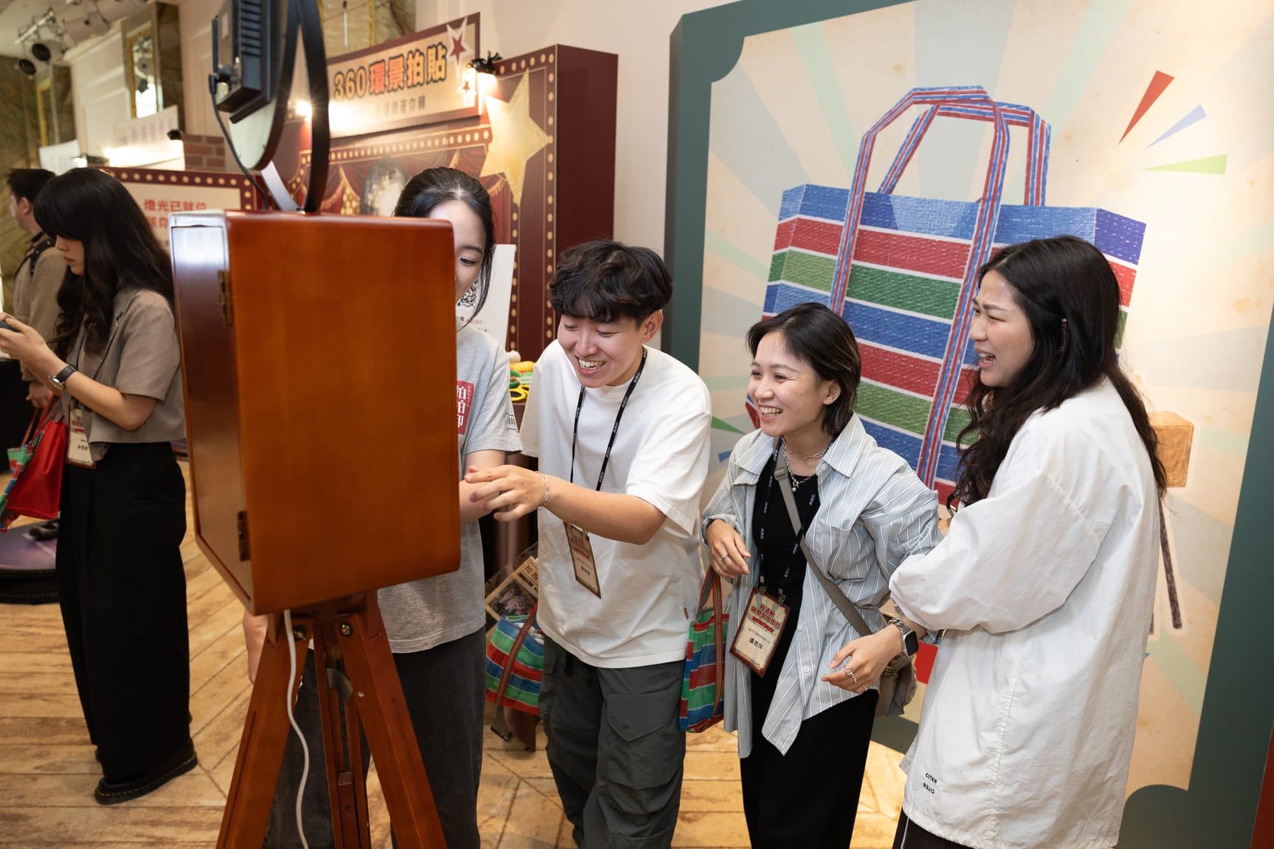 Guests gathered around a retro wooden photo booth, working the screen together