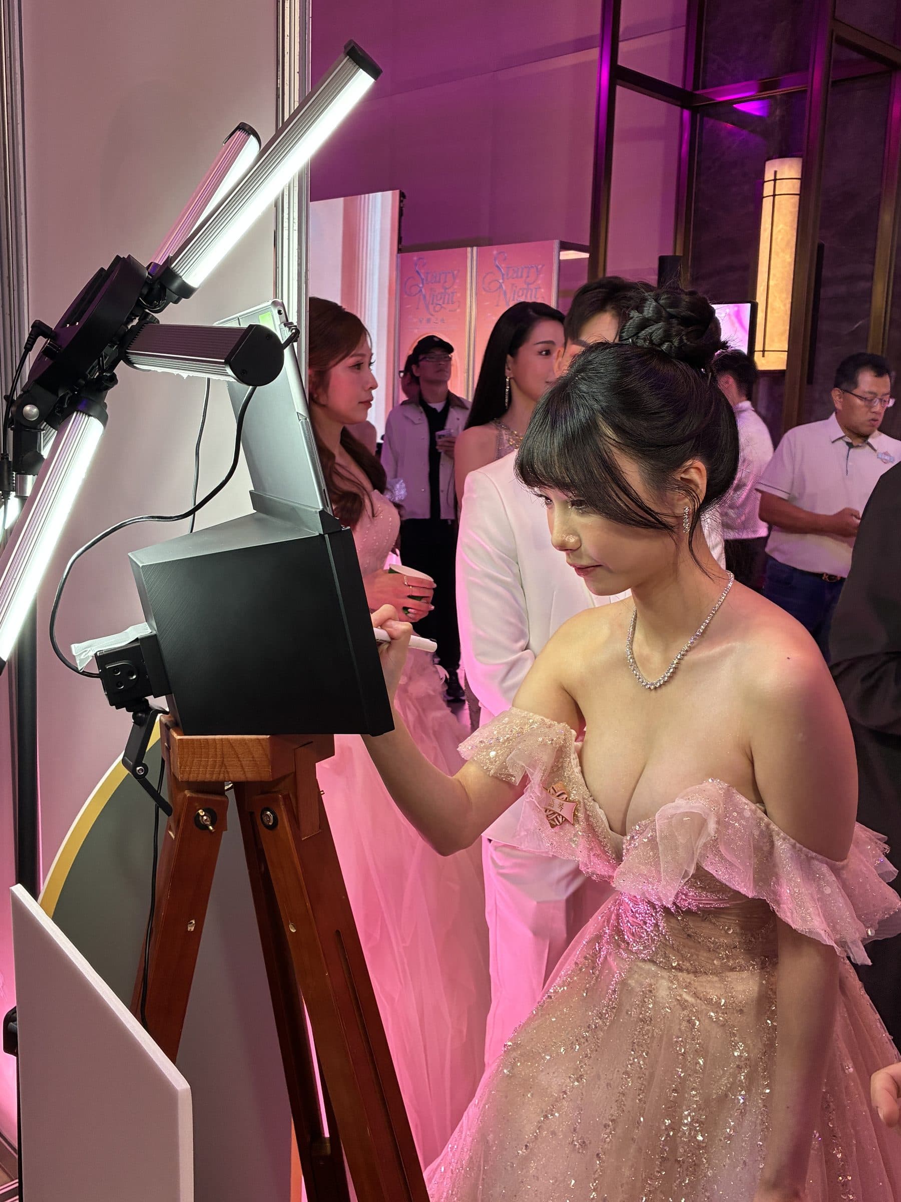 At a black-tie event, a guest in evening dress signing at the booth