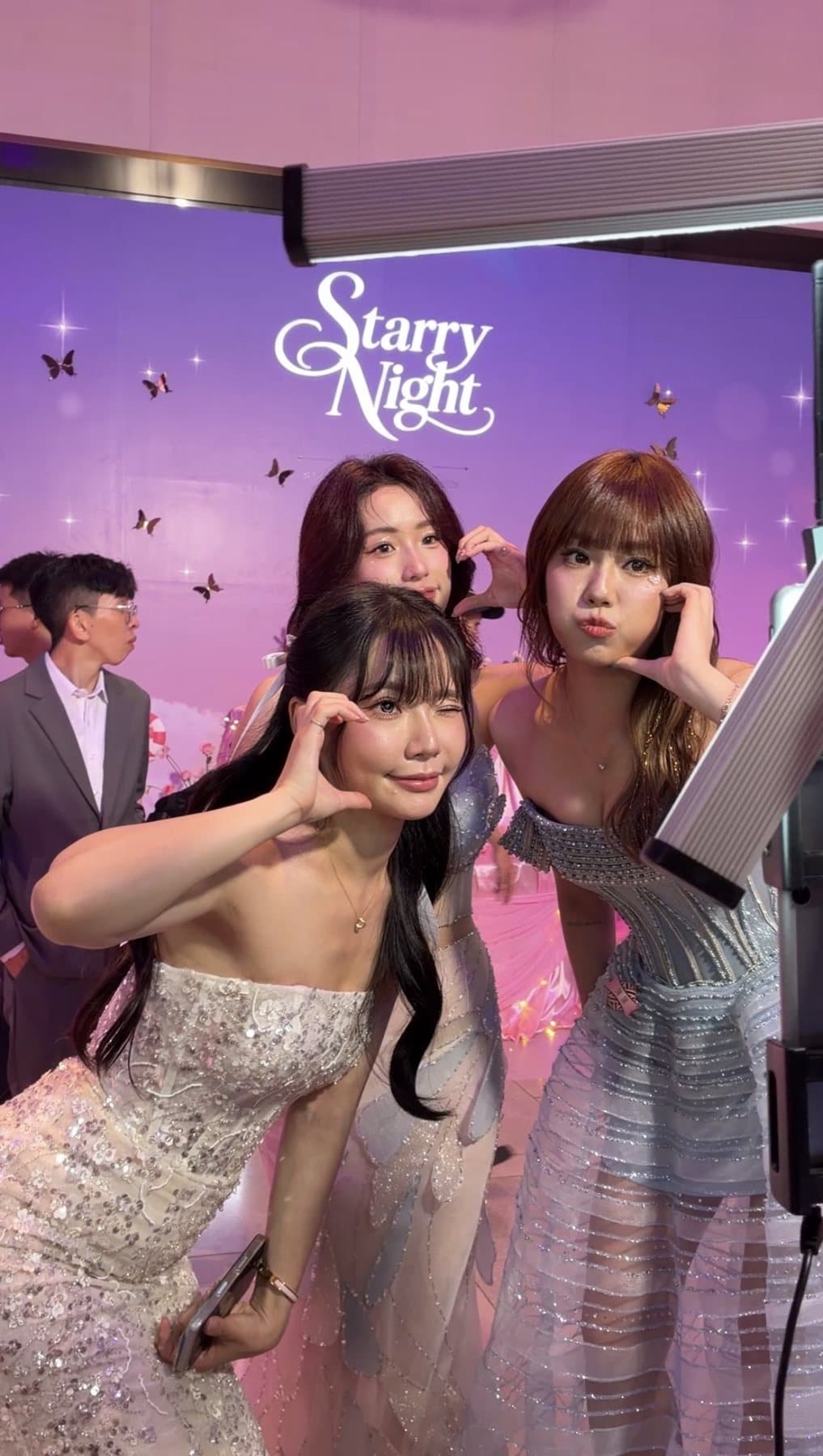 Three guests posing with their signed photo cards in front of the Starry Night key visual