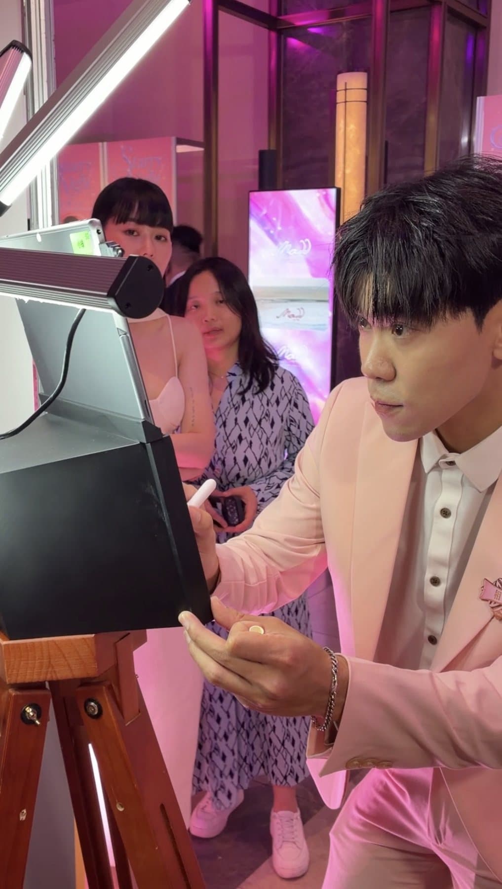 Two guests using the camera sign booth together, both live on the screen