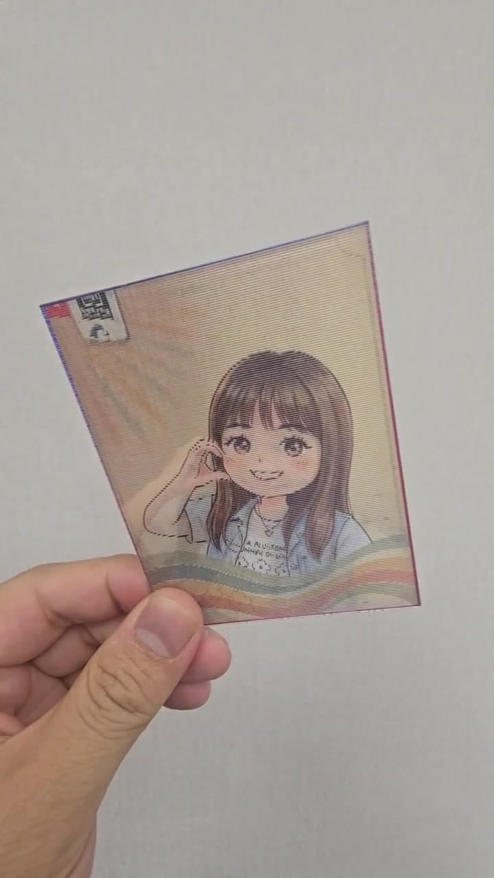 Real footage: a hand tilts the lenticular card and the photo alternates with its cute illustration face