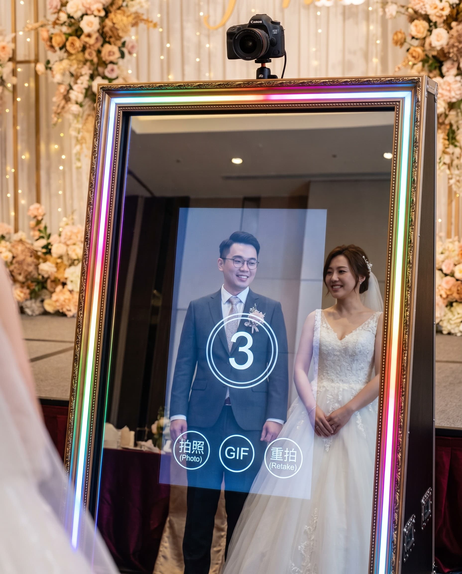 A couple posing at the magic mirror photo booth at a wedding