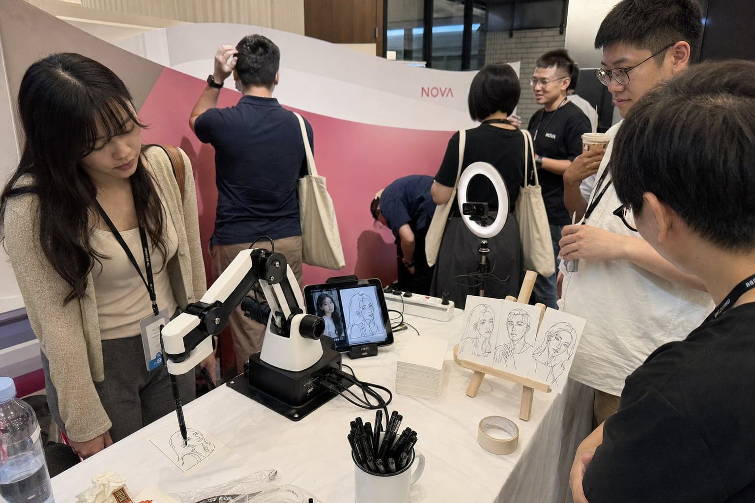 Full table setup: sketch robot, tablet, camera, paper and sample sketches on an easel
