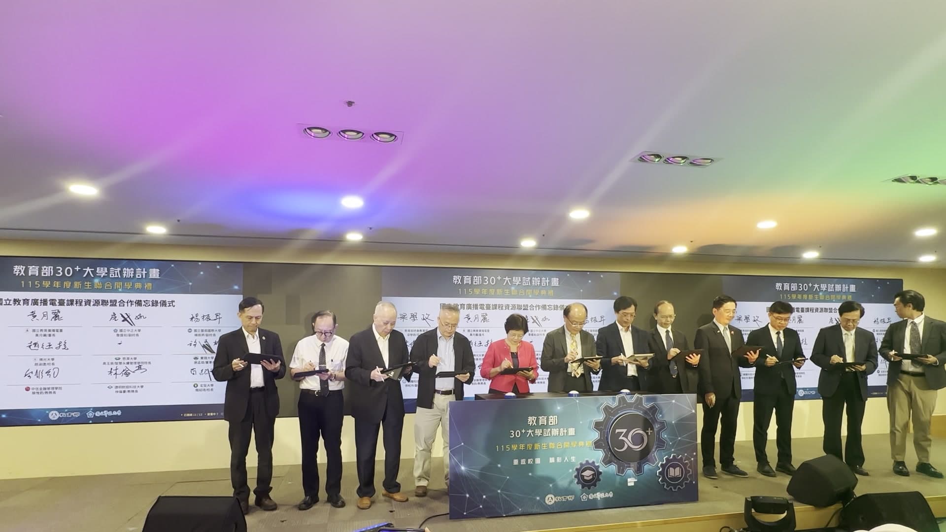 Audience view: 12 university presidents and officials signing on iPads at the same time in front of the LED wall