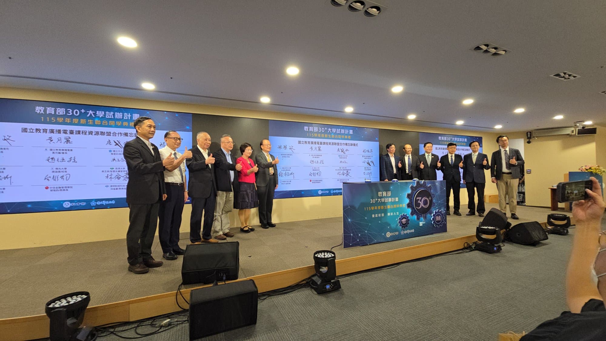 12 VIPs applauding for the group photo in front of the completed wall