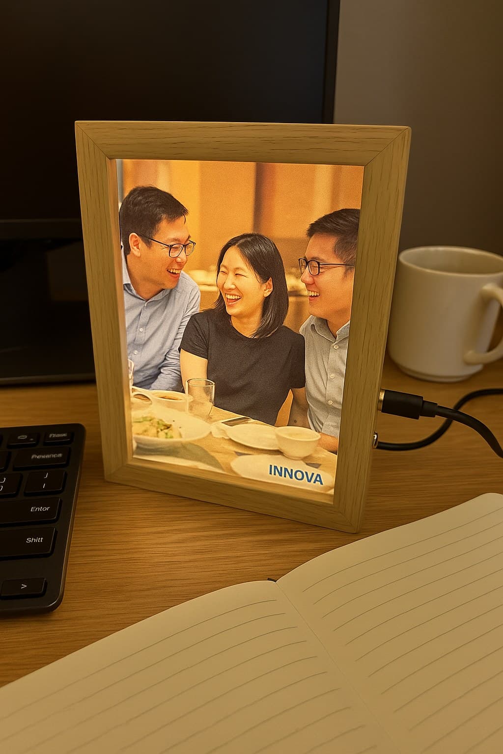 A Time Photo Lamp glowing on an office desk with a team celebration photo and logo
