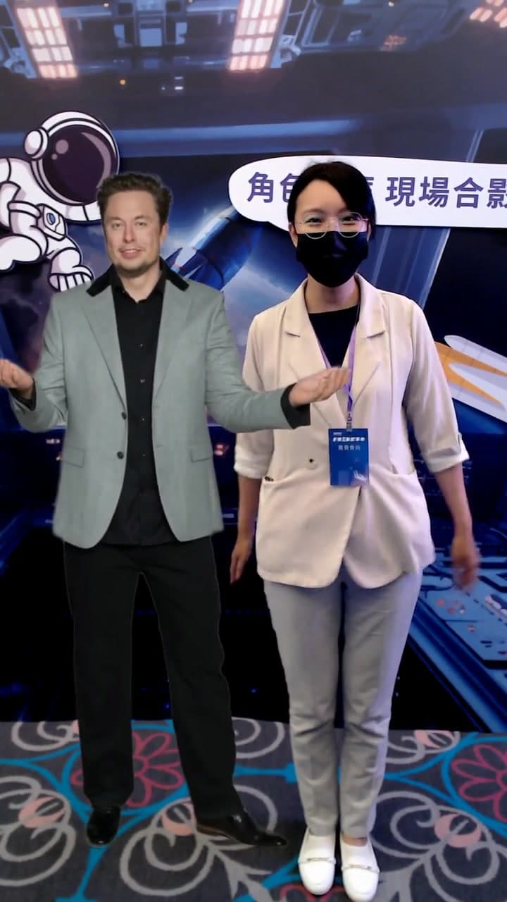 Guest posing side by side with a virtual Elon Musk against the event key visual