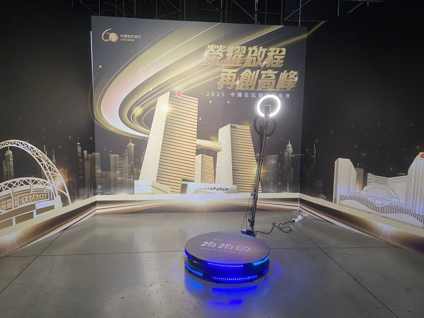 A 360 video booth platform set before a golden stage backdrop at a bank annual gala