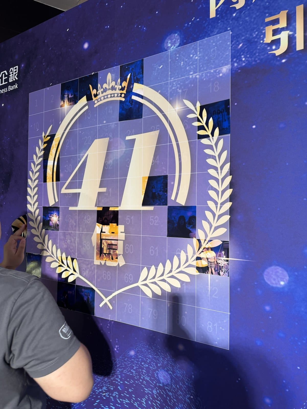 A deep-blue starry-sky "40" mosaic wall at a bank anniversary, with guests posing for photos