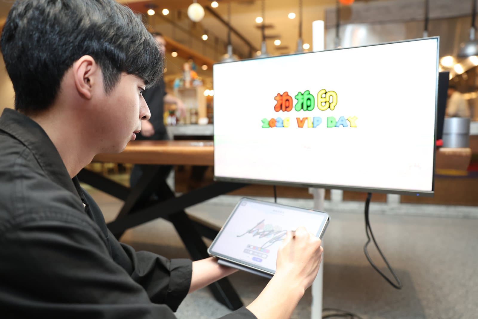 A guest hand-signs on the tablet, the stroke syncing onto the big screen