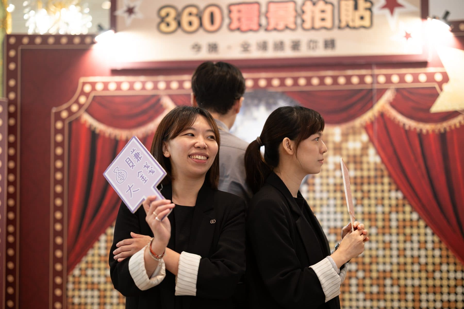 Two guests back to back with props in front of the 360 vintage-cinema backdrop