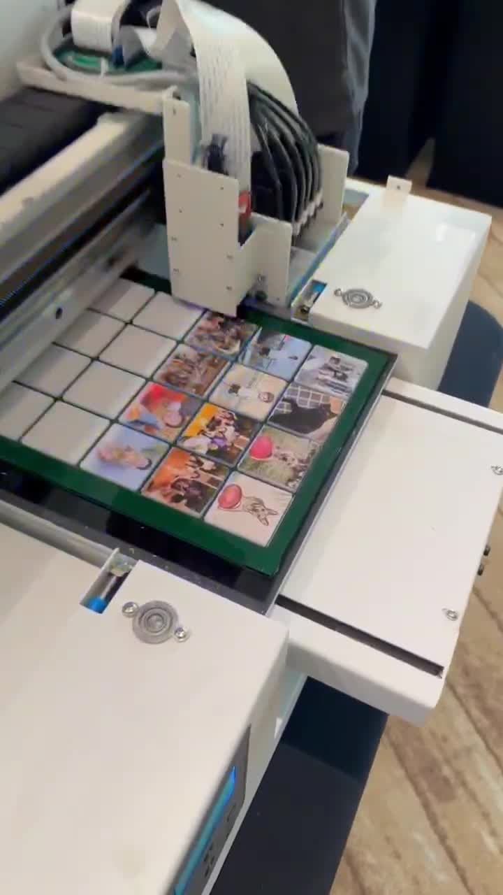 The UV flatbed head sweeping the full jig under ultraviolet light, with photographic and illustrated panels in the cells